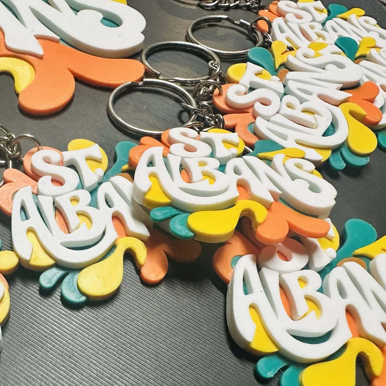 Close-up of raised white St. Albans lettering above teal, orange, and yellow shapes